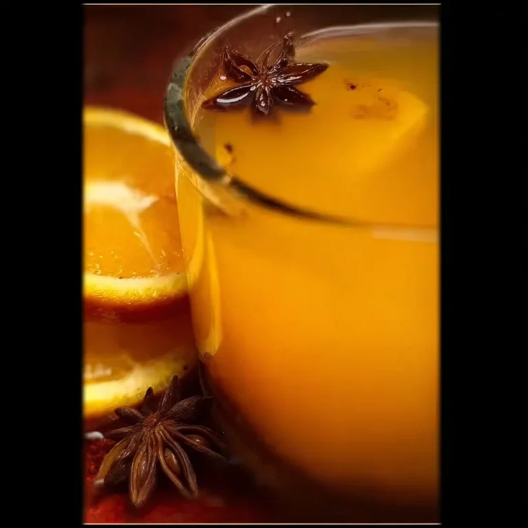 A steaming cup of aromatic mulled cider with spices and fruits