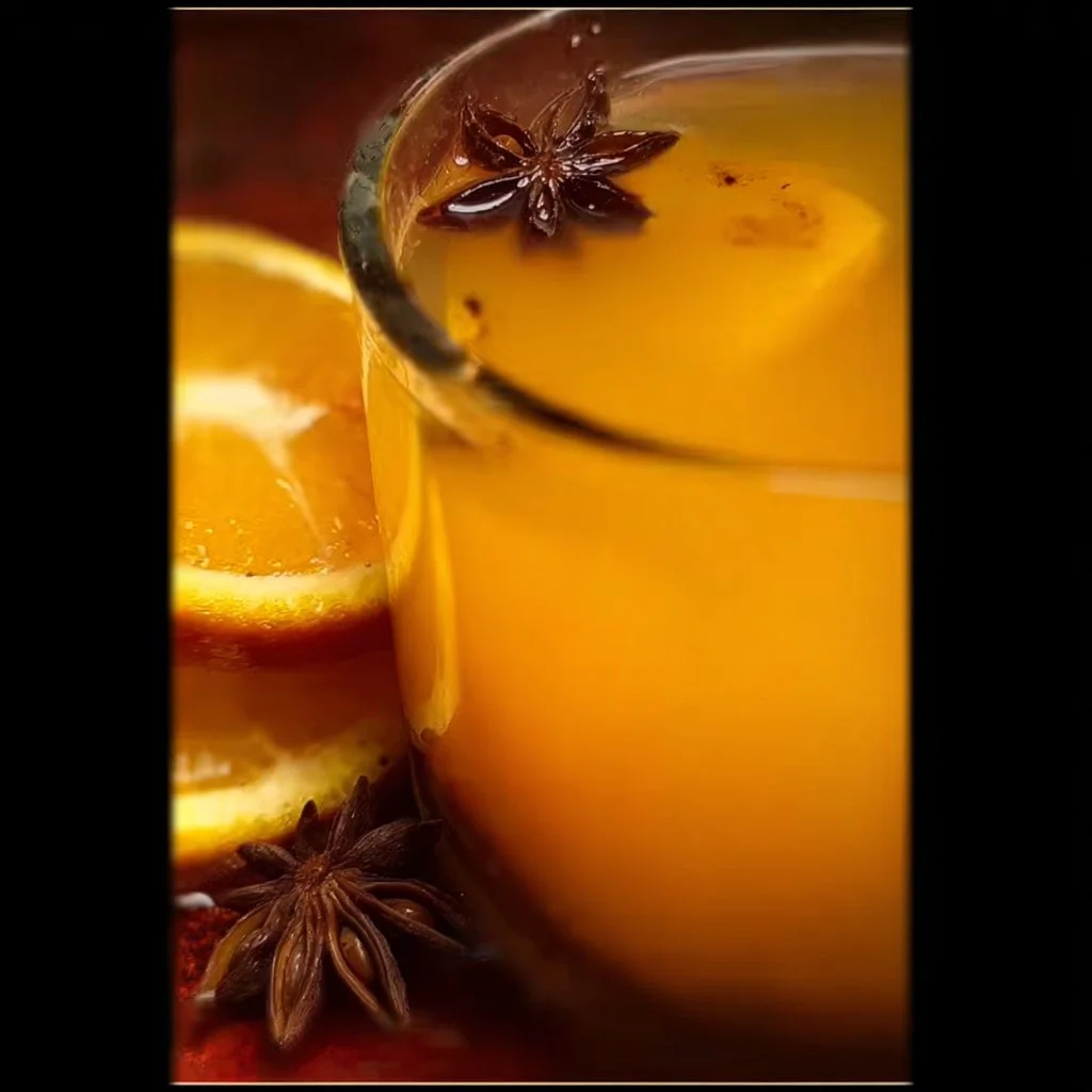 A steaming cup of aromatic mulled cider with spices and fruits
