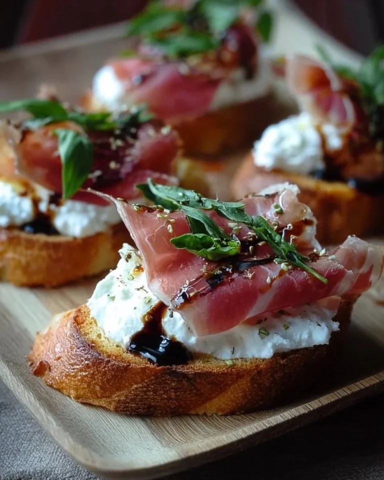 Burrata Crostini topped with prosciutto on a wooden board